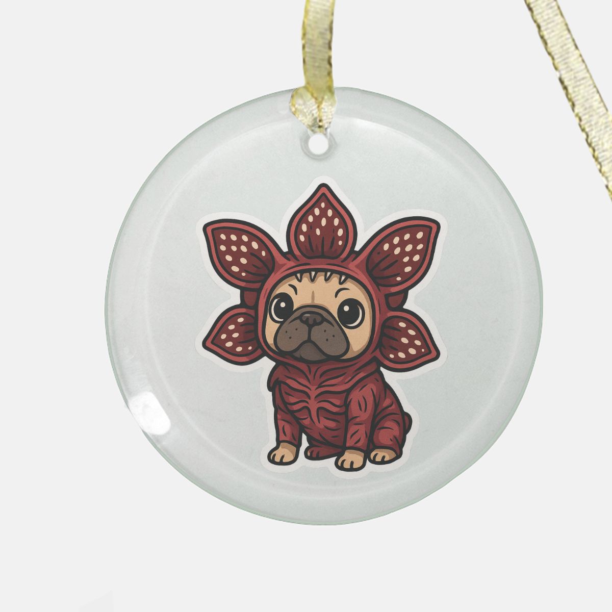 Clear round glass ornament featuring Demo-Frenchie, a cute French Bulldog in a spooky-cute red creature costume, printed on one side with a gold ribbon for hanging.